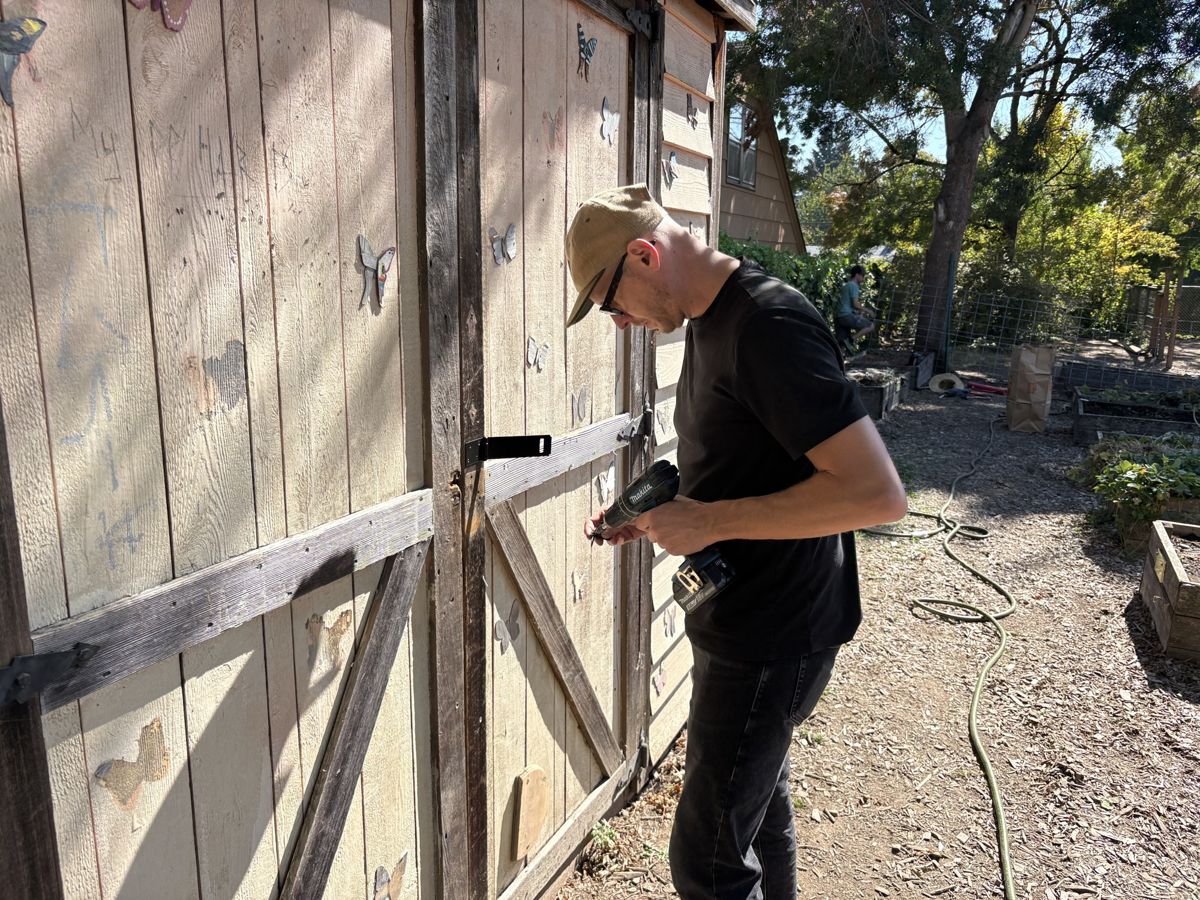 Jay securing the garden shed door with a drill