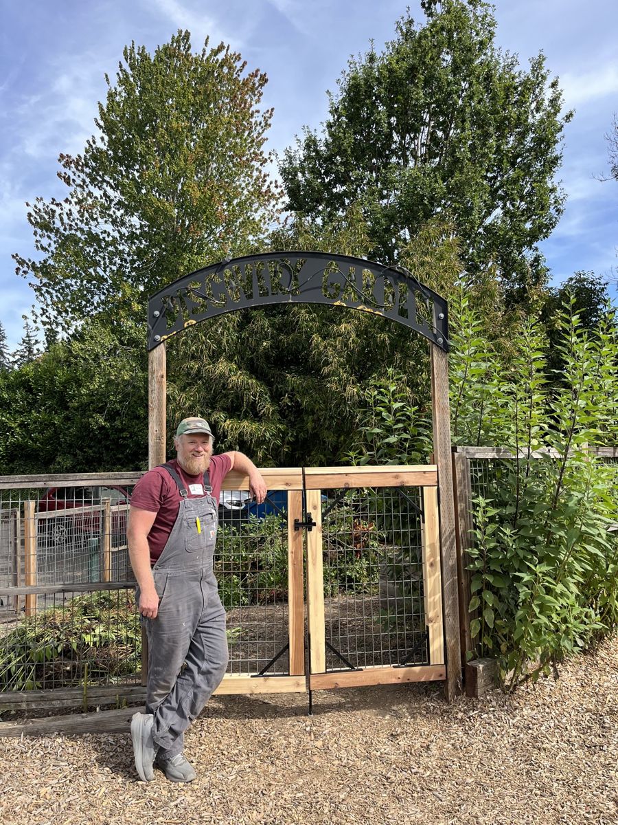 Adam leaning against the garden's new wooden gate